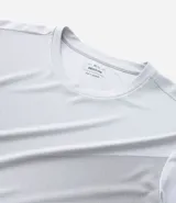 Remera deportiva gris de poliéster con cuello redondo y mangas cortas. Presenta un diseño degradado en el frente y protección UV.