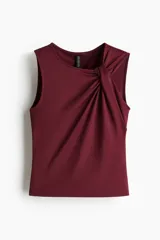 Top sin mangas color vino tinto, de tejido elástico y ajuste entallado, con un nudo drapeado en el hombro que crea un escote asimétrico.