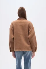 Campera estilo camisa (shacket) de tejido tipo borrego o sherpa color crema, con cuello y tapeta de pana marrón. Posee dos bolsillos frontales con tapa y botones a presión.