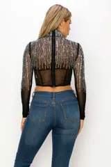 Top tipo corset de tul elastizado semi transparente color negro, con cuello alto y mangas largas. Cubierto con pedrería plateada.
