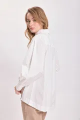 Camisa blanca de mangas largas con hombreras y cuello clásico.