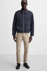 Pantalón chino azul marino, corte skinny fit, confeccionado en tejido de algodón con elasticidad. Cuenta con bolsillos frontales y traseros de vivo. Cierre frontal con cremallera y botón.