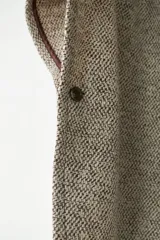 Capa con cuello, cierre frontal con botones y bolsillos delanteros. Confeccionada en lana fina sin teñir, diseñada exclusivamente por Don Baez.