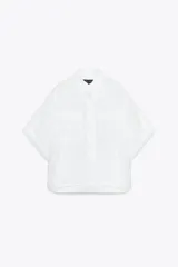 Camisa blanca de corte holgado, con cuello solapa, manga corta con dobladillo y bolsillos de plastrón en el delantero. Tiene bajo asimétrico con aberturas laterales y cierre frontal con botones ocultos.