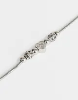 Pulsera plateada flexible con dijes de metal y strass, incluyendo un dije de corazón.