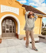 Sweater tejido de lana color gris claro, de corte holgado y mangas largas. Presenta flecos en el ruedo.