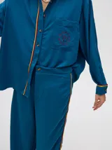 Pantalón azul petróleo de corte holgado y tiro alto, con caída recta y detalle de diseño al costado con ribete rojo y amarillo.