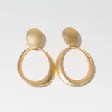Aros colgantes dorados con forma ovalada y textura cepillada.
