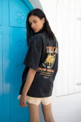 Remera negra de corte oversize con estampa trasera con un sol y texto en color naranja.