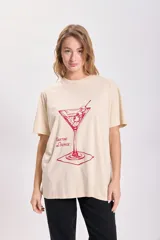 Remera color beige de corte holgado con estampado de una copa de martini en color rojo.