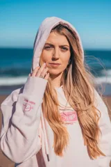 Hoodie rosa con capucha y cordones ajustables. Estampado en la espalda con motivos playeros: sol, olas, conchas y flores de hibisco.