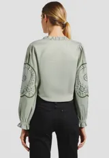 Blusa color crema de algodón con volados, corte holgado, escote en V y lazos para atar.