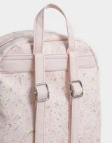 Mochila negra con estampado de margaritas blancas, confeccionada en cuero sintético. Cuenta con correas regulables, manija superior, acceso con cierre, bolsillo frontal con cierre y tag de cuerina. Incluye un pouch extraíble.