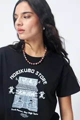 Remera negra de algodón con estampado blanco de un edificio de estilo oriental y texto en inglés y japonés.