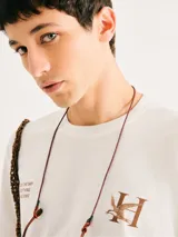 Camiseta blanca de algodón con cuello redondo y mangas cortas. Estampa rectangular con borde negro que contiene la frase "NATURAL ATMOSPHERE" en letras mayúsculas y una imagen de montañas y mar.