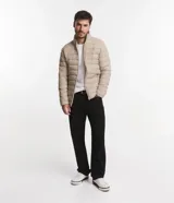 Campera puffer ultraligera color beige, con cuello alto, cierre por cremallera y bolsillos con cremallera. Incluye bolso de almacenamiento.