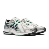Championes New Balance modelo 1906R, color blanco con detalles en plateado y verde. Presentan el logo "N" en los laterales y tecnología de amortiguación N-ergy en la entresuela.