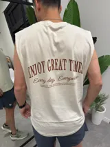 Musculosa beige con estampado marrón que dice "ENJOY GREAT TIMES" y otras frases en la espalda. Corte holgado y sin mangas.