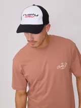 Gorra con visera Rusty, con frente blanco y logo bordado en negro y rojo, malla trasera negra y visera negra.