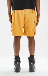 Bermuda cargo color mostaza de corderoy liviano, con bolsillos amplios con solapa, fuelle y detalles en cinta gross, elástico en la cintura y calce oversize.