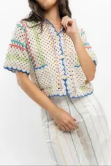 Saco tejido a crochet con diseño a rayas multicolores y detalles en azul.