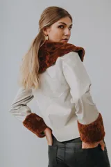 Chaqueta marrón de cuero Napa con cuello y puños de lana color crema, cierre frontal con cremallera y corte a la cintura.