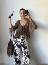 Blusa marrón de encaje con volados, mangas acampanadas y lazo en el escote.