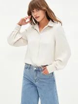 Camisa blanca de manga larga con cuello clásico y cierre frontal con botones.