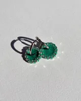 Par de aros colgantes con argolla de acero quirúrgico, dije circular de resina negra y borde de strass plateado.