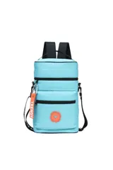 Mochila matera acolchada color celeste, con correas negras ajustables para llevar como mochila o bandolera. Presenta cierres negros y un aplique circular naranja con un corazón en el frente. Incluye un llavero colgante naranja con la palabra "TRENDY".