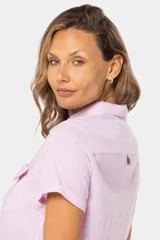 Camisa de lino color salmón, de corte clásico, con cuello camisero, medio abotonada, de manga corta y con dos bolsillos frontales con solapa.