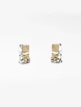 Pendientes grandes de metal con diseño abstracto y textura rugosa, combinando acabados dorado y plateado. Cierre tipo broche.