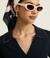 Blusa de punto color blanco, con cuello polo, escote en V y mangas cortas. Detalle de mini perlas aplicadas en el cuello.