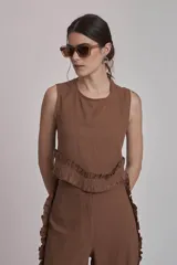 Conjunto de dos piezas color marrón, compuesto por un top sin mangas con volado en el ruedo y un pantalón ancho de tiro alto con volados decorativos a lo largo de las costuras laterales.