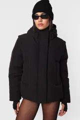 Campera puffer beige de corte oversize, confeccionada en textil impermeable. Cuenta con capucha forrada con tancas y elástico, cuello alto, cierre frontal con cartera y abrojo, bolsillos ribete con cierre, mangas desmontables con mitones y cintura ajustable con elástico y tancas. Incluye cinta gross estampada para transportarla al hombro y bolsillo interno con cierre invisible.