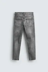 Pantalón de jean negro ajustado al cuerpo desde la cintura hasta el tobillo, de tiro medio y tejido elástico. Diseño de cinco bolsillos con lavado efecto roto y cierre frontal con cremallera y botón.