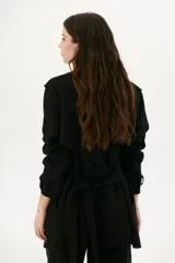 Trench simil gamuza color marrón, con cuello de solapa muesca, cuatro botones delanteros, bolsillos laterales y cinturón a la altura de la cintura.