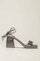 Sandalias plateadas de cuero con tacón bloque, plataforma delantera y tiras finas para atar al tobillo.