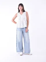 Blusa blanca sin mangas con escote en V y cierre frontal con botones.