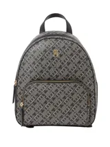 Mochila Tommy Hilfiger confeccionada en poliuretano con estampado integral de monograma TH. Presenta un compartimento principal con cierre, un bolsillo frontal con cremallera y herrajes metálicos dorados, incluyendo el logo de la marca en el frente. Cuenta con correas de hombro ajustables y un asa superior.