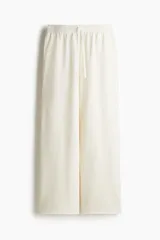 Pantalón deportivo de algodón color crudo, corte holgado, cintura elástica con cordón ajustable, bolsillos laterales y bajos sin rematar.