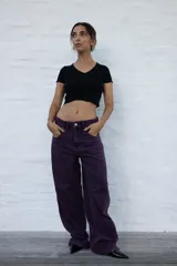 Jean de mujer color violeta oscuro, de corte holgado y tiro bajo. Presenta un efecto lavado y bolsillos traseros con costuras decorativas.