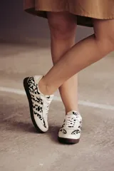 Zapatillas Adidas Samba con estampado animal print en blanco y negro, detalles en cuero beige y suela de goma color caramelo.