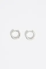 Par de aros tipo argolla plateados con cierre a presión y logo grabado en el contorno.