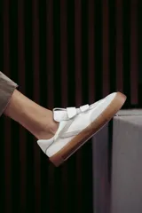 Zapatillas urbanas blancas con detalles en gris y suela color caramelo. Presentan cierre con tiras de velcro.