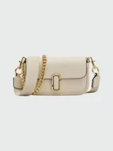 Bolso bandolera Marc Jacobs The Mini, color crema, con correa ancha de tela con logo de la marca y cadena dorada decorativa.