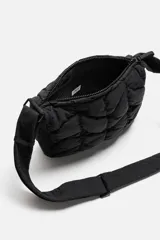Bandolera negra acolchada de tejido técnico con cierre de cremallera. Tiene dos bolsillos interiores, uno con cremallera. El asa de hombro es ajustable.