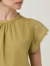 Blusa color verde oliva de algodón orgánico y ramie, con cuello redondo y mangas cortas con detalle de crochet.