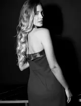 Vestido de fiesta corto strapless, color negro, confeccionado en crepe. Presenta escote recto con aplique de moño en satén y tajo en la parte delantera.