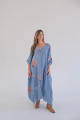Vestido largo celeste con estampado de flores color salmón, corte holgado, mangas 3/4 con ajuste en los puños y ruedo irregular con terminación desflecada.